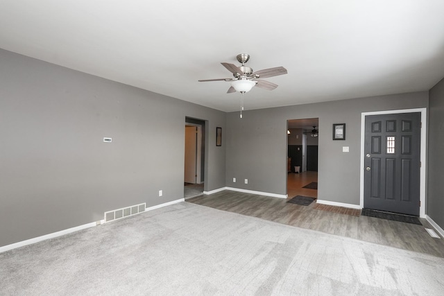 spare room with ceiling fan, wood finished floors, visible vents, and baseboards