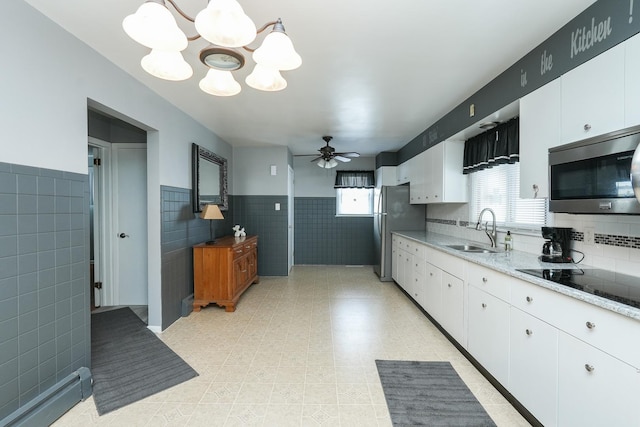 kitchen with white cabinetry, appliances with stainless steel finishes, baseboard heating, and a sink