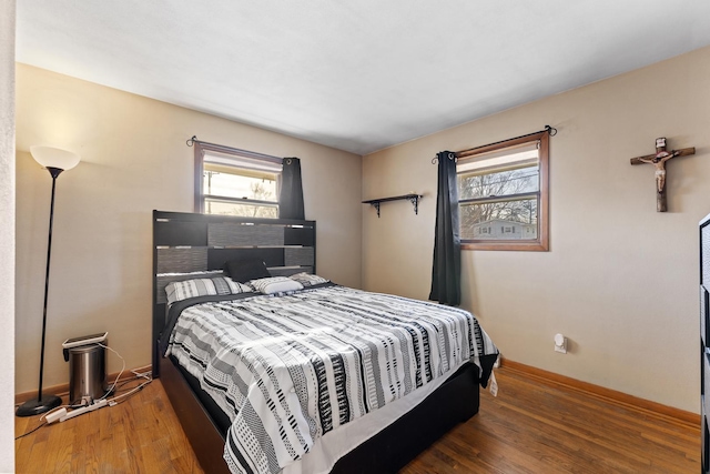 bedroom with multiple windows and dark hardwood / wood-style floors