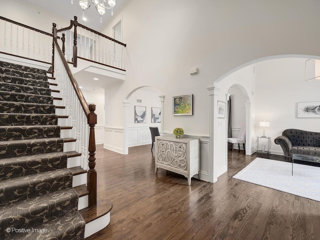 foyer entrance with dark hardwood / wood-style flooring, a towering ceiling, and ornamental molding