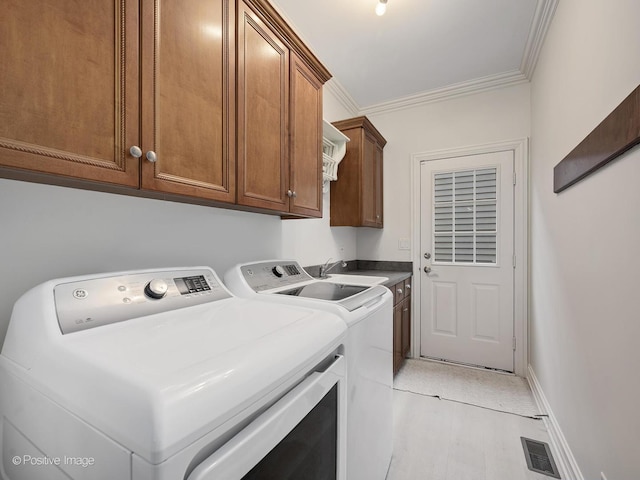 laundry area featuring cabinets, washing machine and dryer, sink, and crown molding