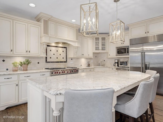 kitchen with pendant lighting, a center island, built in appliances, and a kitchen breakfast bar