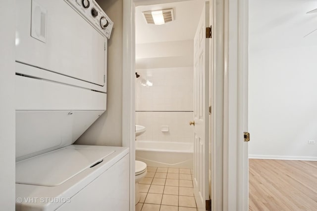 laundry room featuring stacked washer / dryer and light tile patterned flooring