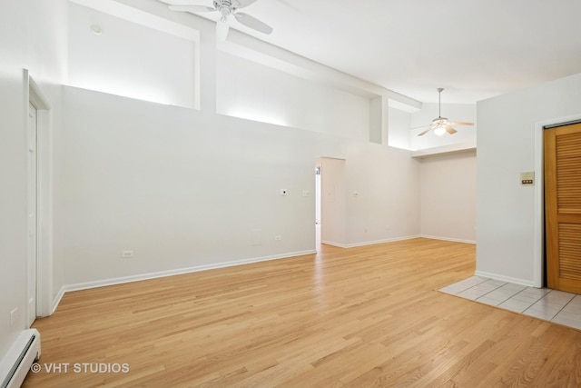 unfurnished living room featuring a ceiling fan, a baseboard radiator, light wood-style flooring, high vaulted ceiling, and baseboards