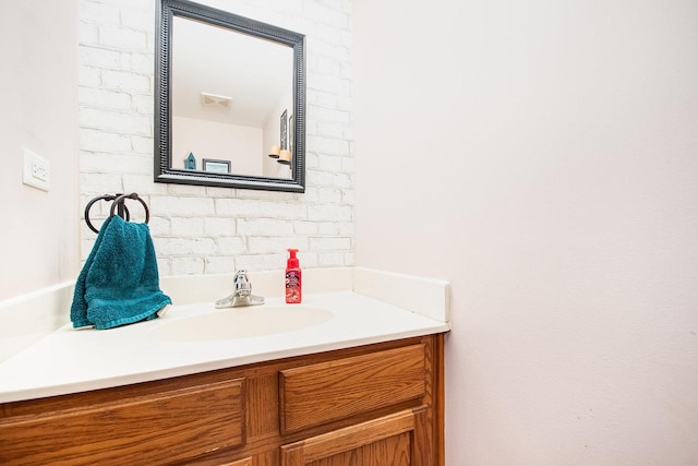 bathroom with vanity and brick wall