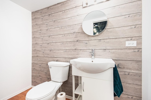 bathroom featuring vanity, hardwood / wood-style flooring, wooden walls, and toilet