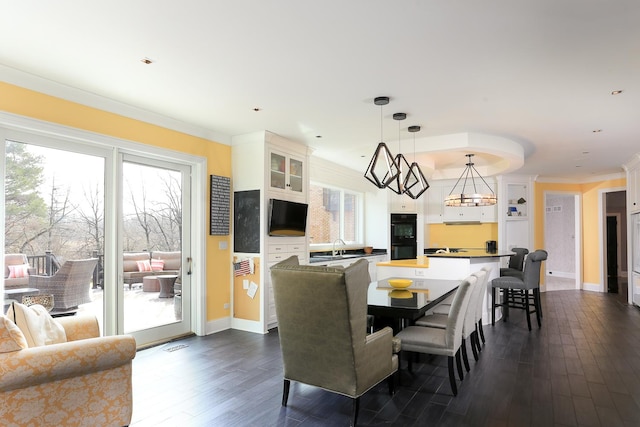 dining area with dark wood-type flooring, a healthy amount of sunlight, and crown molding