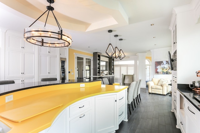 kitchen with white cabinetry, decorative light fixtures, a chandelier, and crown molding