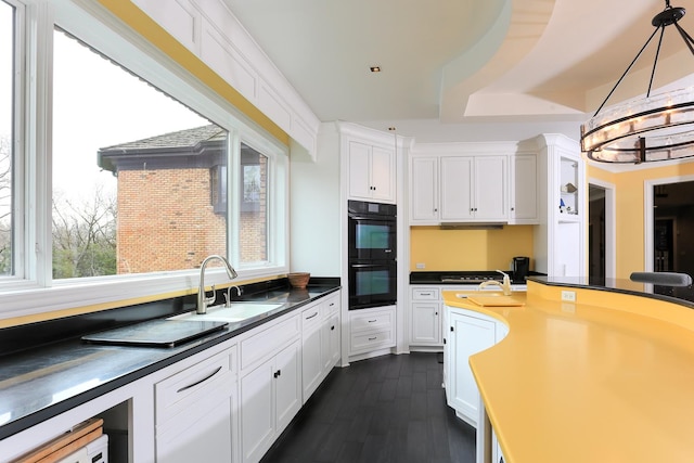 kitchen with sink, white cabinetry, decorative light fixtures, dark hardwood / wood-style flooring, and black double oven