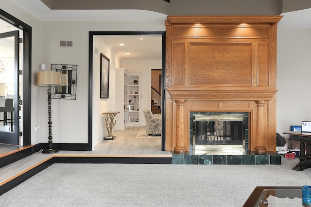 living room with crown molding, a tile fireplace, and light hardwood / wood-style flooring