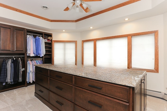 walk in closet with a baseboard radiator, light colored carpet, ceiling fan, and a tray ceiling