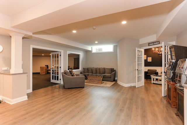 living room featuring wood-type flooring, french doors, and ornate columns