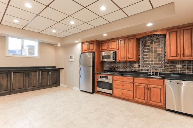 kitchen featuring a drop ceiling, stainless steel appliances, sink, and backsplash