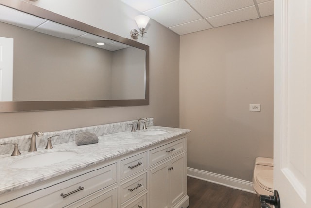 bathroom featuring hardwood / wood-style flooring, a paneled ceiling, vanity, and toilet