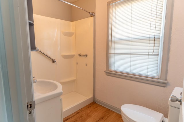 bathroom with a sink, wood finished floors, a shower stall, and toilet