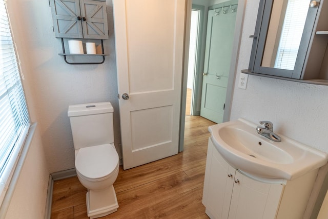 bathroom with a textured wall, vanity, toilet, and wood finished floors