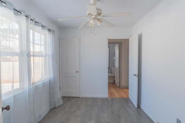 unfurnished bedroom featuring a ceiling fan, baseboards, wood finished floors, and ornamental molding