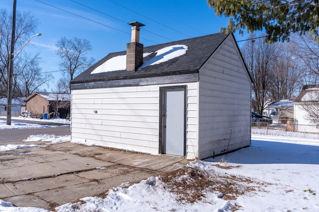 snow covered garage featuring fence