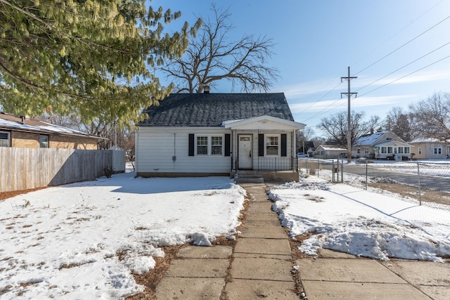 bungalow-style home featuring a shingled roof and fence