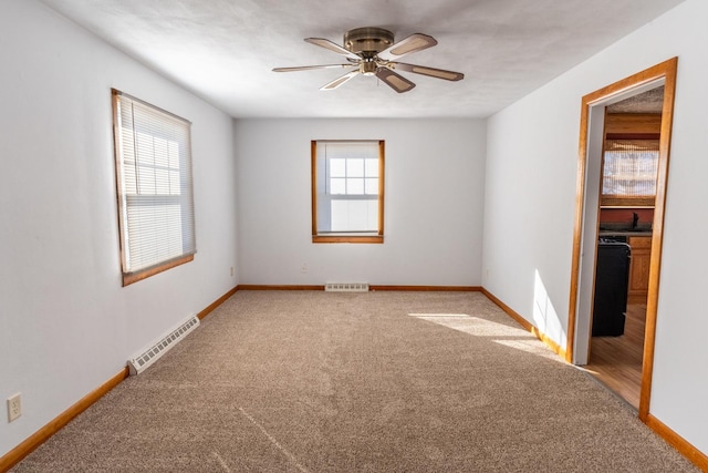 carpeted spare room featuring baseboards, visible vents, and a healthy amount of sunlight