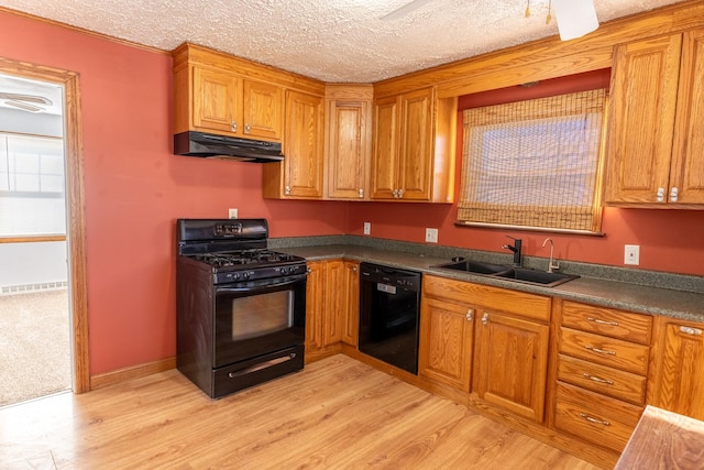 kitchen featuring dark countertops, brown cabinetry, a sink, under cabinet range hood, and black appliances