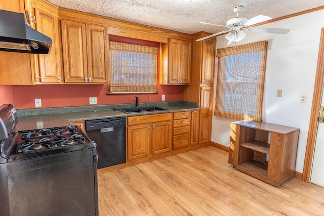 kitchen featuring brown cabinetry, dark countertops, under cabinet range hood, black appliances, and a sink