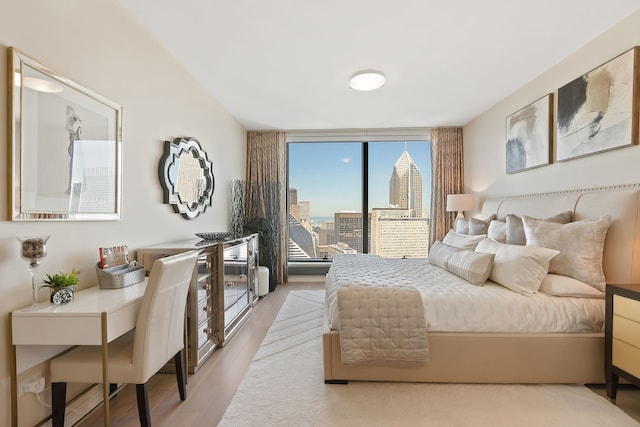 bedroom with floor to ceiling windows and light hardwood / wood-style flooring