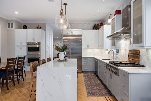 kitchen featuring gray cabinets, appliances with stainless steel finishes, sink, a center island, and wall chimney range hood