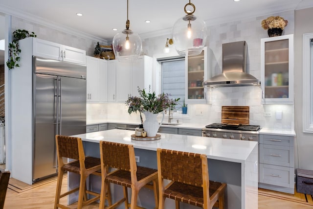 kitchen featuring crown molding, stainless steel built in fridge, a kitchen island, pendant lighting, and range hood