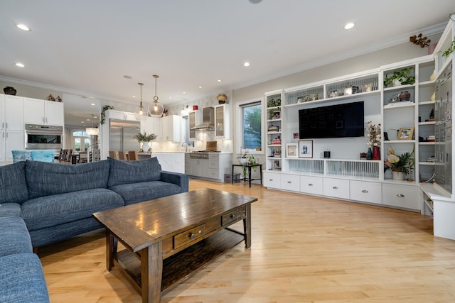 living room featuring ornamental molding, sink, and light wood-type flooring