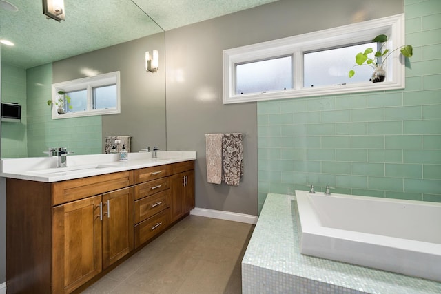 bathroom with vanity, plenty of natural light, a textured ceiling, and a bathtub