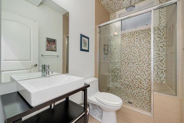 bathroom with an enclosed shower, sink, and toilet