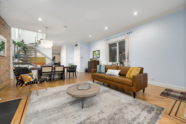 living room featuring ornamental molding, brick wall, an inviting chandelier, and light hardwood / wood-style floors