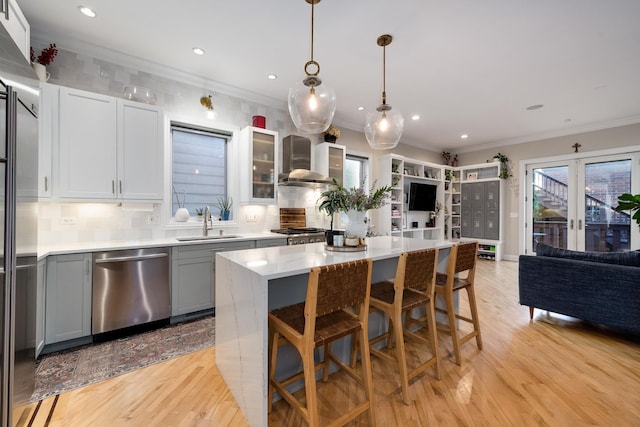 kitchen with gray cabinetry, a center island, decorative light fixtures, stainless steel dishwasher, and wall chimney exhaust hood