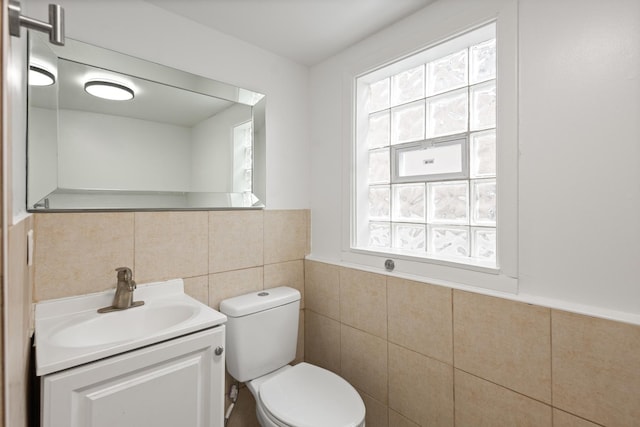 bathroom featuring vanity, toilet, and tile walls