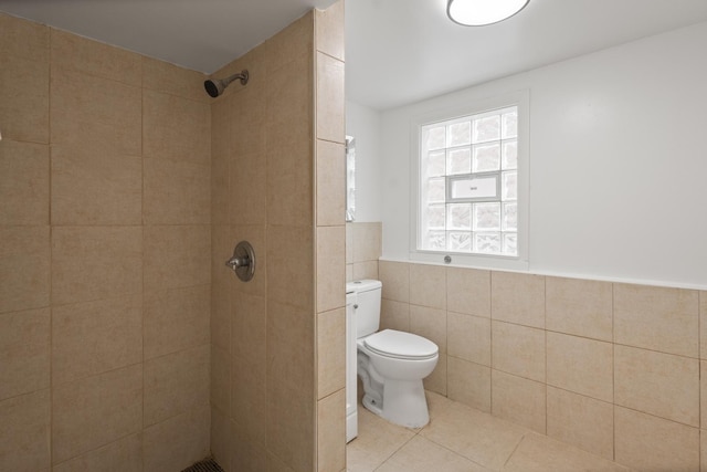 bathroom featuring tile walls, tile patterned floors, toilet, and a tile shower