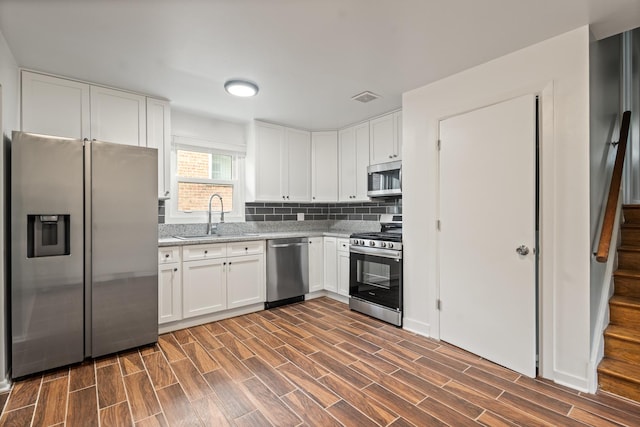 kitchen featuring sink, white cabinetry, stainless steel appliances, light stone countertops, and decorative backsplash