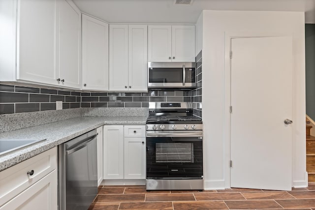 kitchen featuring tasteful backsplash, stainless steel appliances, light stone counters, and white cabinets