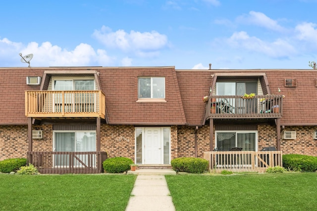 view of property featuring a balcony and a front lawn