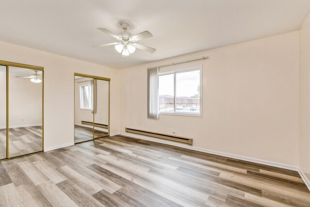 unfurnished bedroom with two closets, light hardwood / wood-style flooring, ceiling fan, and baseboard heating