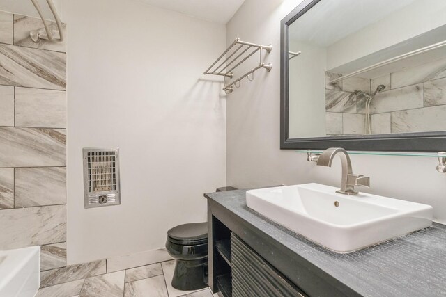 bathroom featuring vanity, heating unit, and toilet