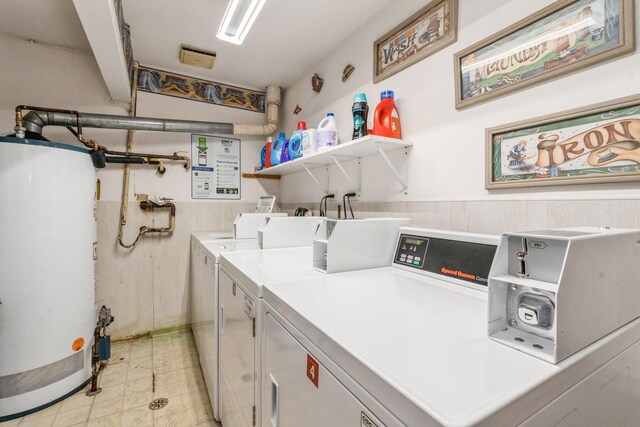 washroom with water heater, separate washer and dryer, and wooden walls