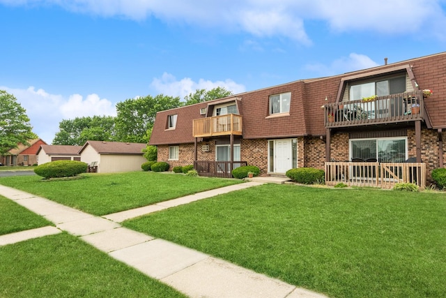 view of property featuring a balcony and a front lawn