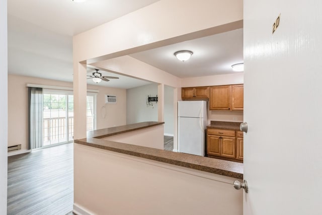 kitchen with an AC wall unit, hardwood / wood-style floors, white fridge, a baseboard heating unit, and ceiling fan