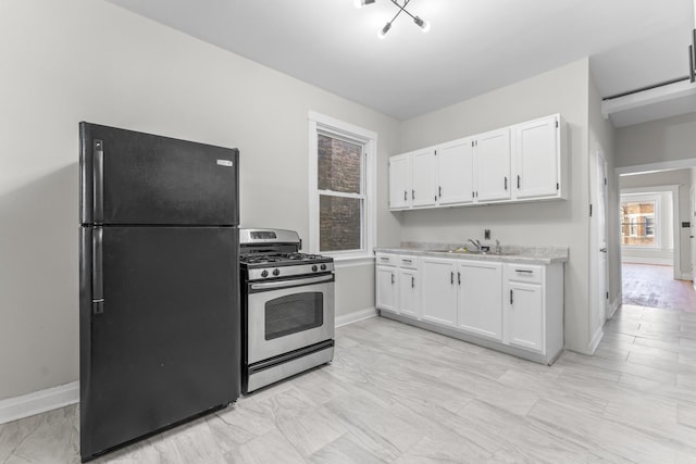 kitchen with stainless steel range with gas cooktop, black refrigerator, sink, and white cabinets