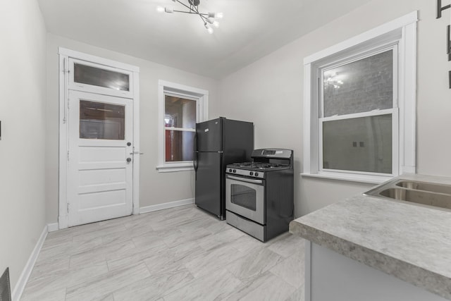 kitchen with black refrigerator, stainless steel range with gas cooktop, and sink