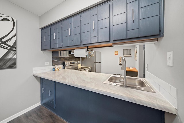 kitchen featuring dark wood-type flooring, blue cabinetry, sink, stainless steel appliances, and decorative backsplash