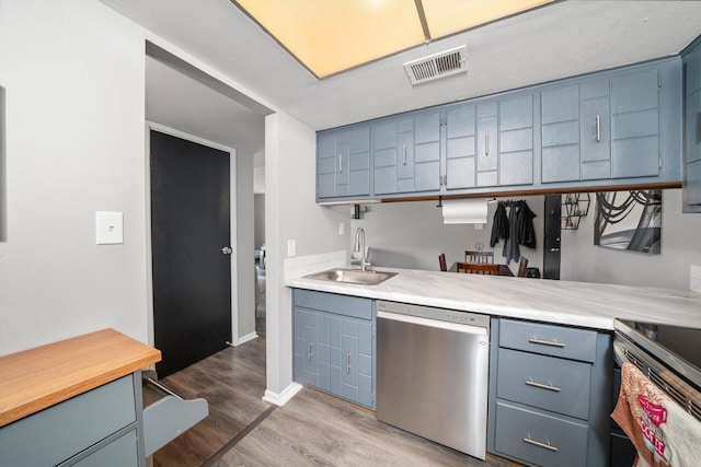 kitchen featuring blue cabinets, dishwasher, wood-type flooring, and sink