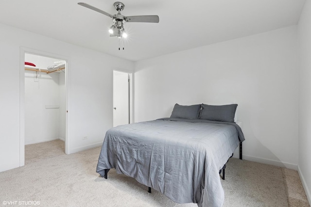 carpeted bedroom with a spacious closet and ceiling fan