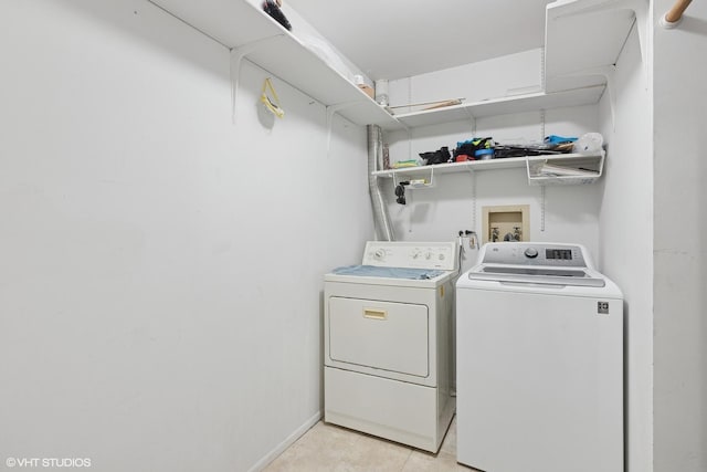 laundry area with independent washer and dryer and light tile patterned floors